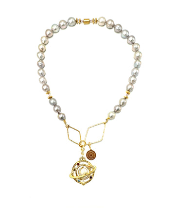 Srebrzysty naszyjnik galaktyki z perłą marki Ewa Mrochen Jewellery na tle białej tkaniny