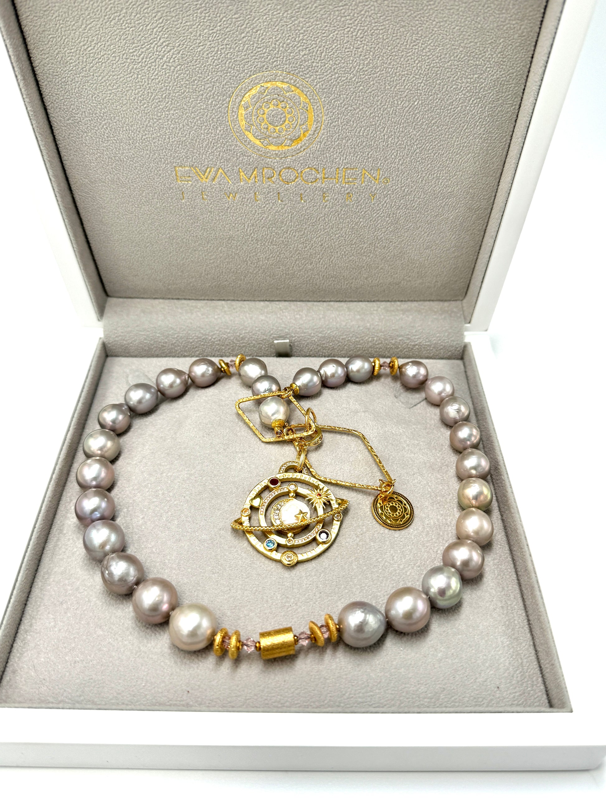 Srebrzysty naszyjnik Galaktyki Pomyślności od Ewa Mrochen Jewellery z perłami i ozdobnymi elementami na tle ciemnego tła