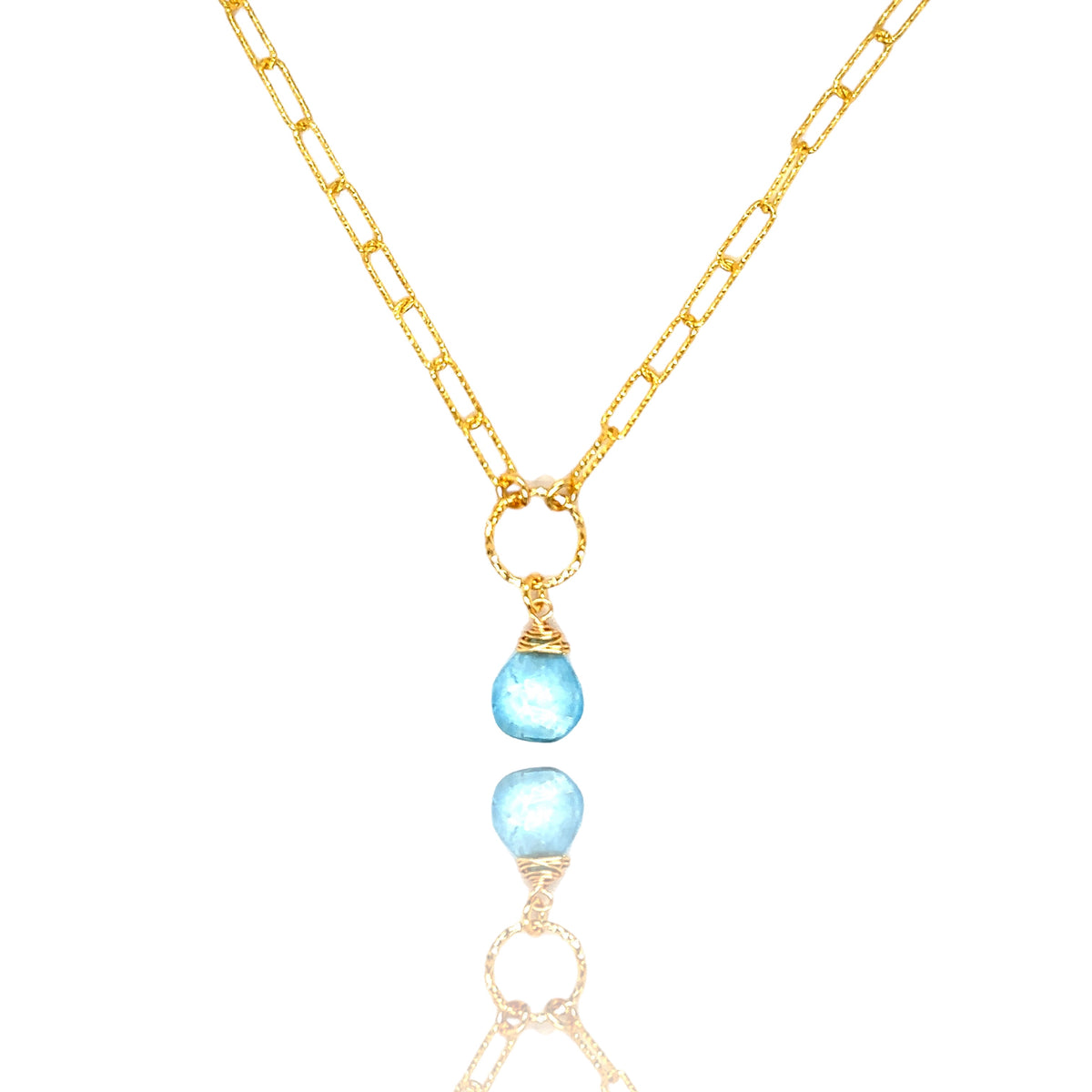 Naszyjnik Topaz Błękitny od Ewa Mrochen Jewellery, elegancki błękitny kamień w srebrnej oprawie, na jasnym tle.