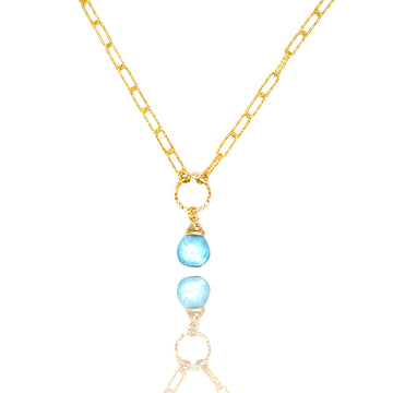 Naszyjnik Topaz Błękitny od Ewa Mrochen Jewellery, elegancki błękitny kamień w srebrnej oprawie, na jasnym tle.